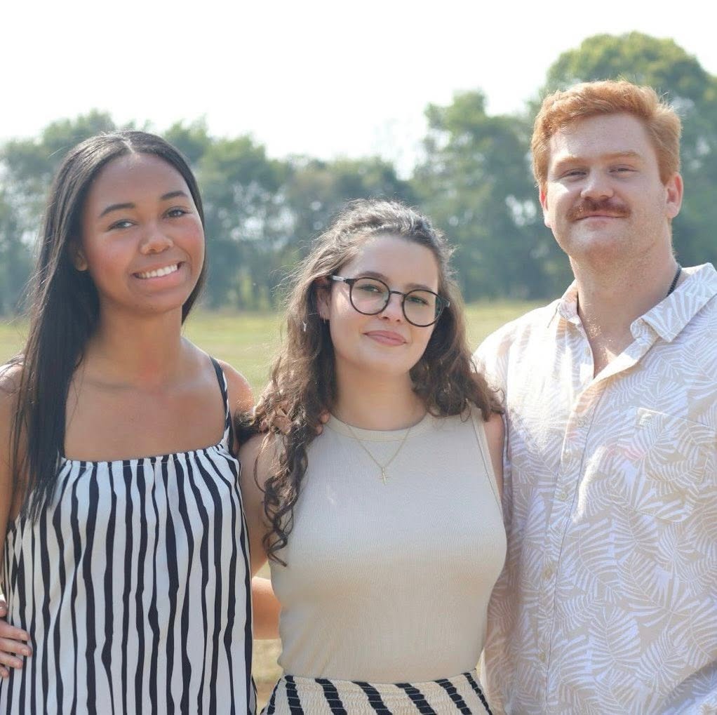 Three young adults smiling together at Awaken Church